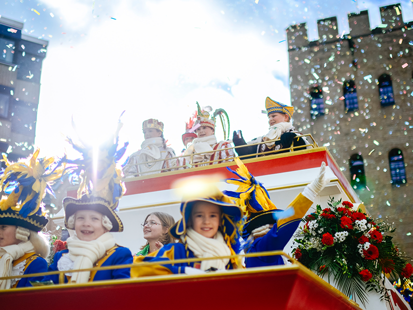 Das Kinderdreigestirn blickt von einem Wagen in die Kamera